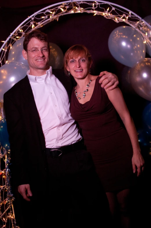 a man and woman pose in front of balloons