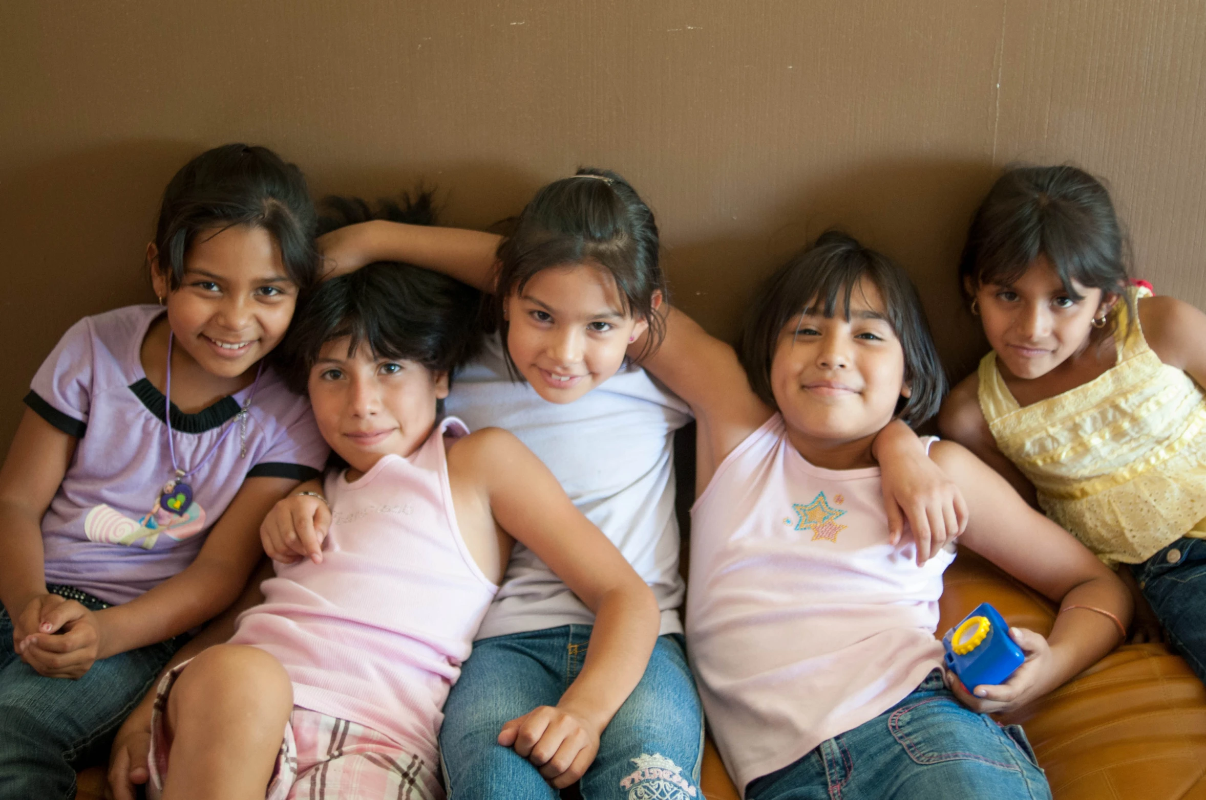 four girls sit together on a couch and smile at the camera