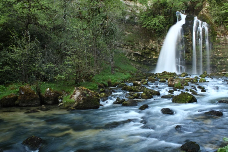 a flowing river is running near some tall rocks