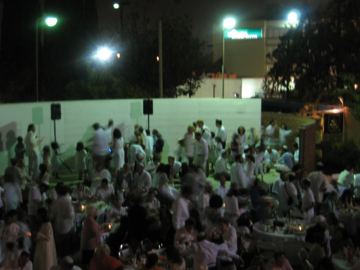 an outdoor party with people standing around tables and chairs