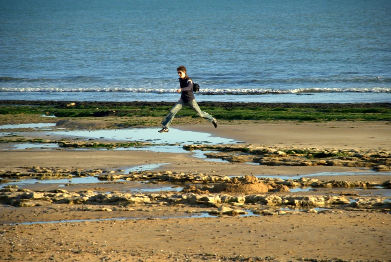 a boy jumping in the air on the beach