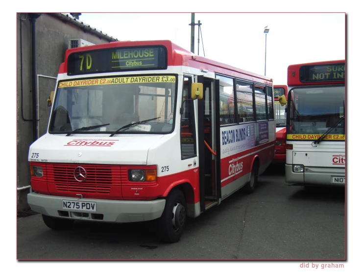 red and white bus stopped at the curb with passengers