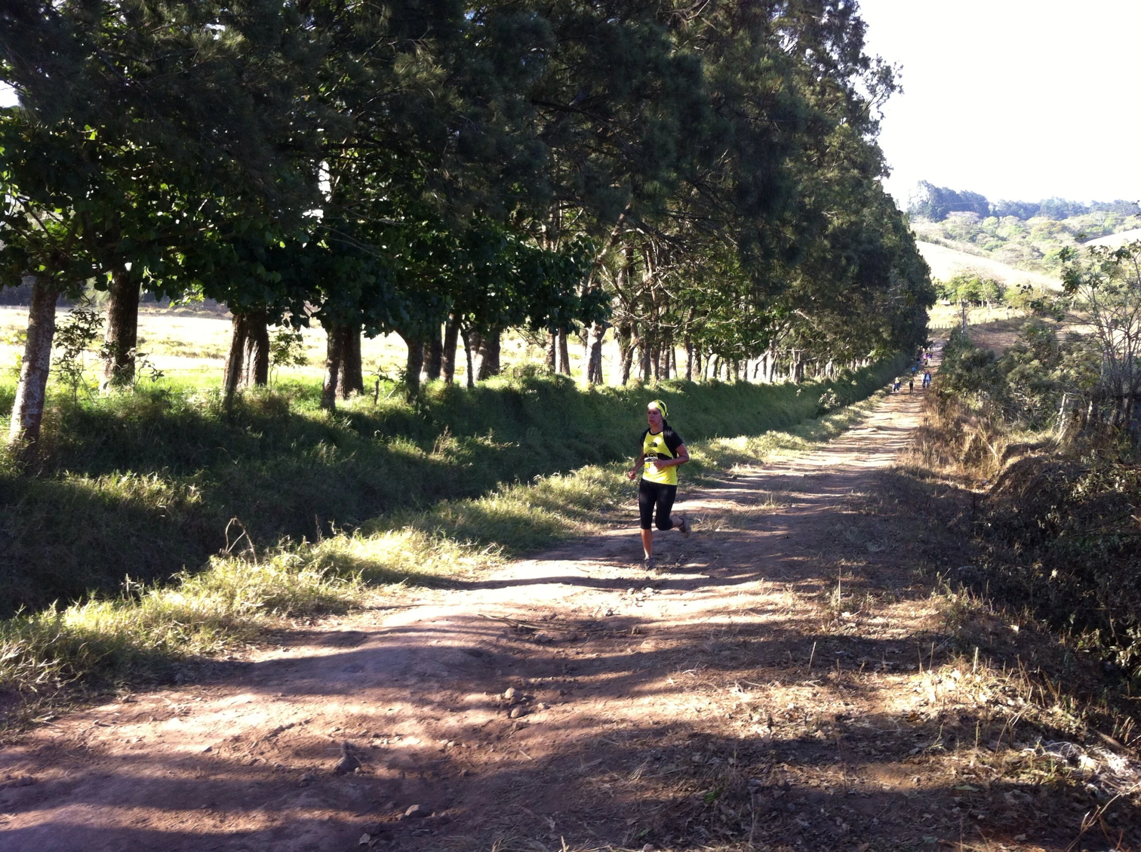 a person running down a dirt road by some trees