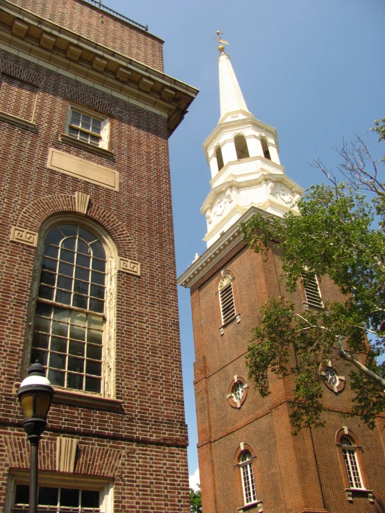 a tall red brick tower with a steeple in the background