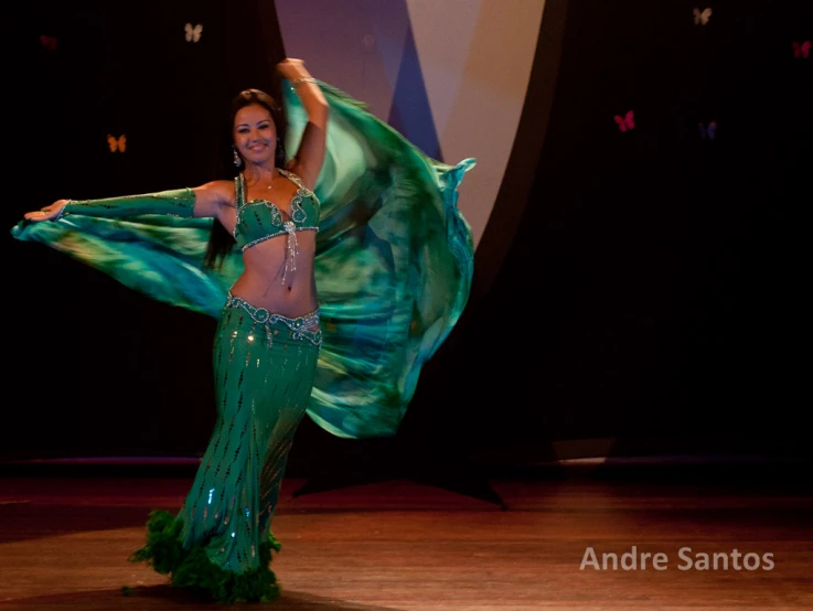 a woman in green and gold costume is on stage