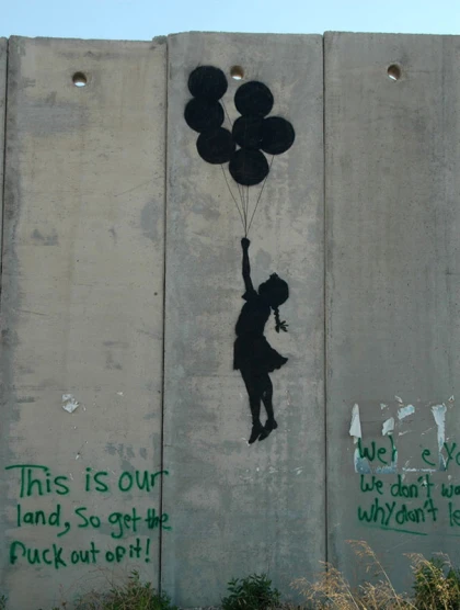 a person holding balloons painted on a concrete wall
