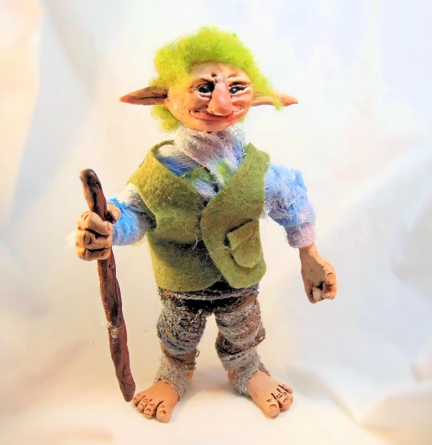 a hand made troll in green clothes holding an open knife