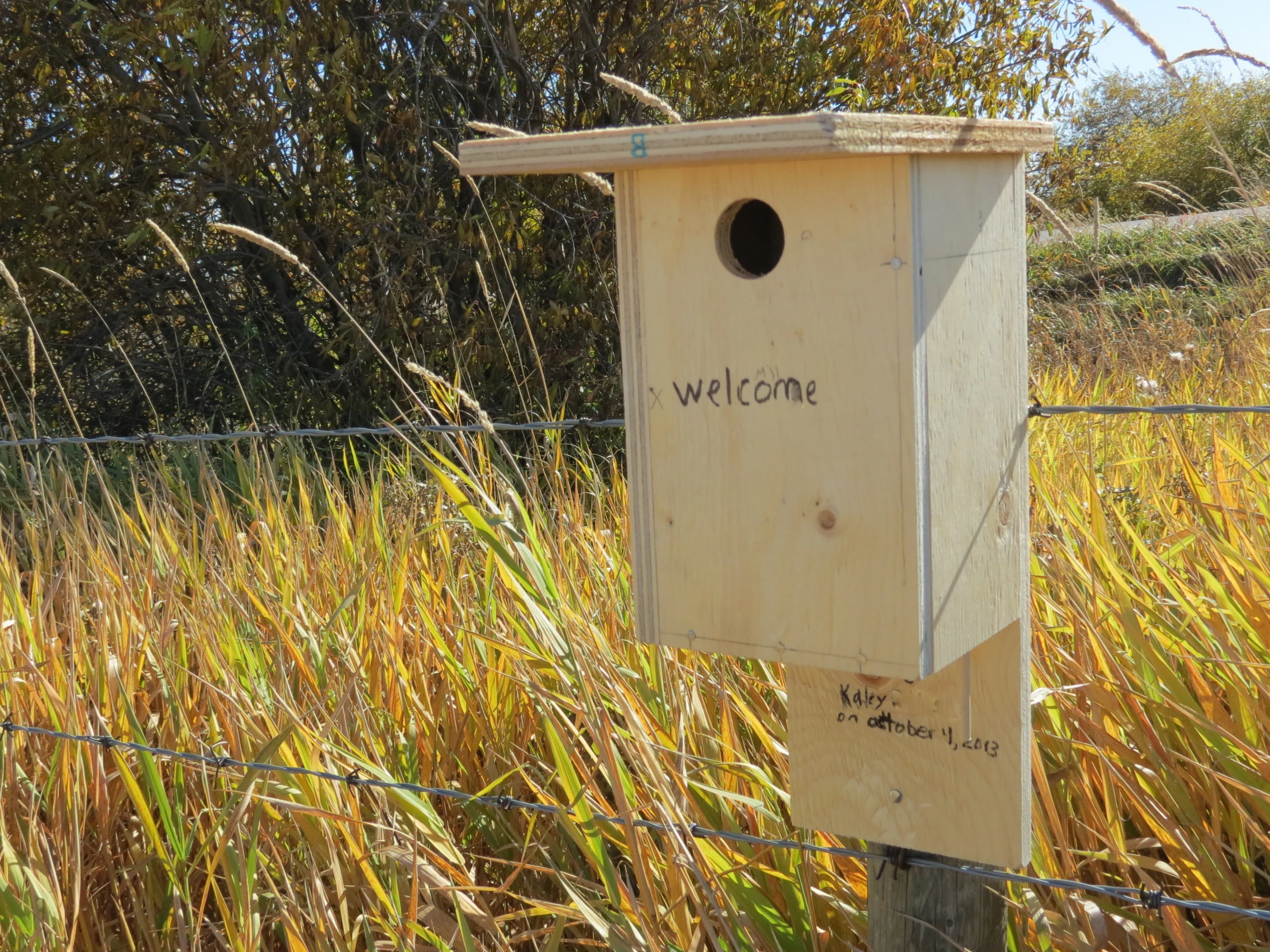 a birdhouse on a post with a welcome sign