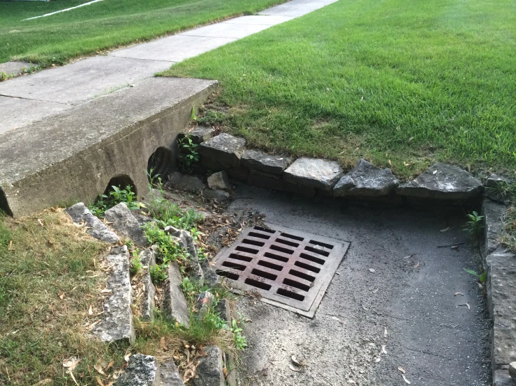 a drain on the side of a road near a sidewalk