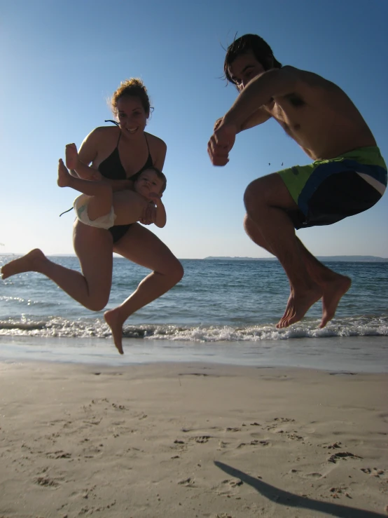 a man and woman jumping on the beach