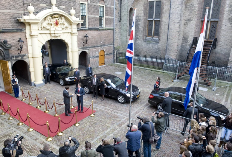 a car parked on a street behind two men in suits