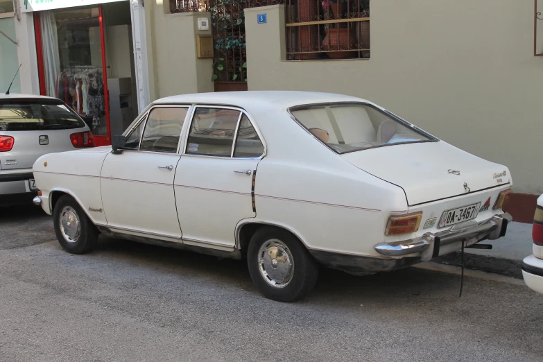 an old car is parked in the street by a wall