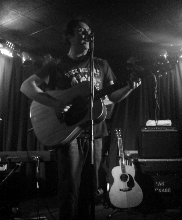 two men playing guitar while standing on stage