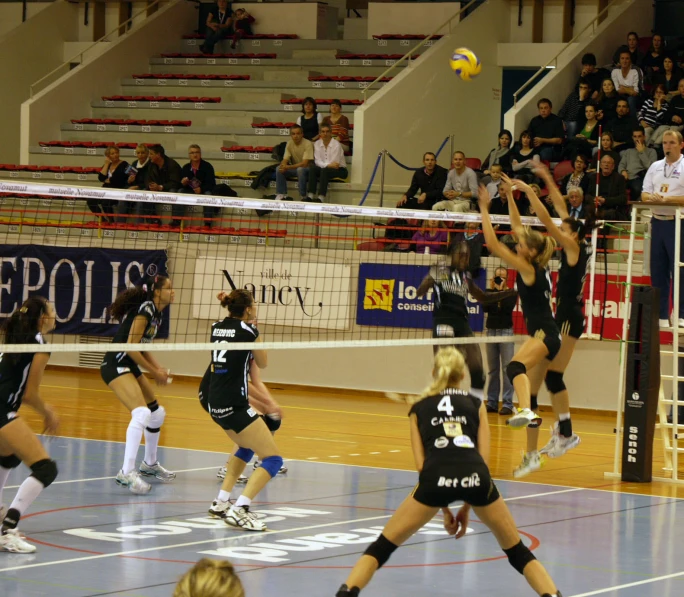 a group of women play volleyball on an indoor court