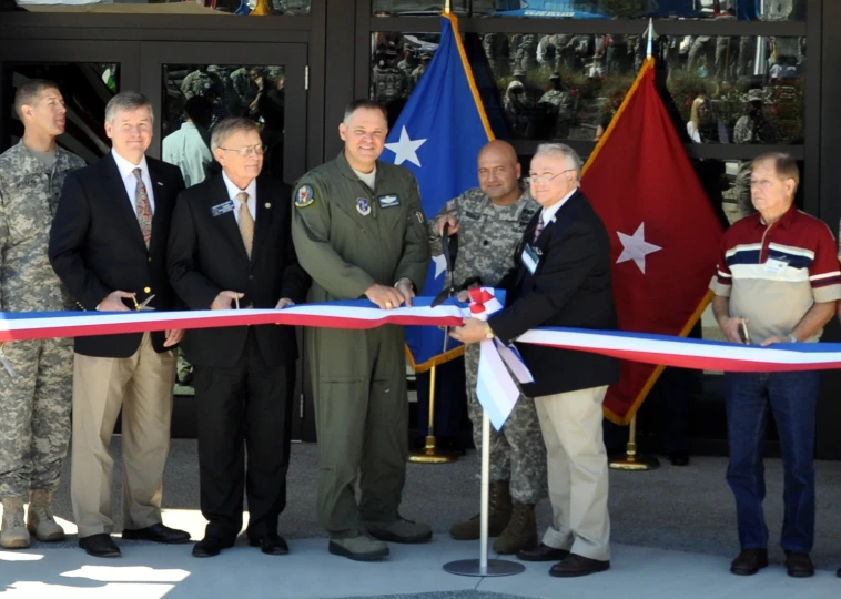 several people are standing behind a ribbon at a ceremony