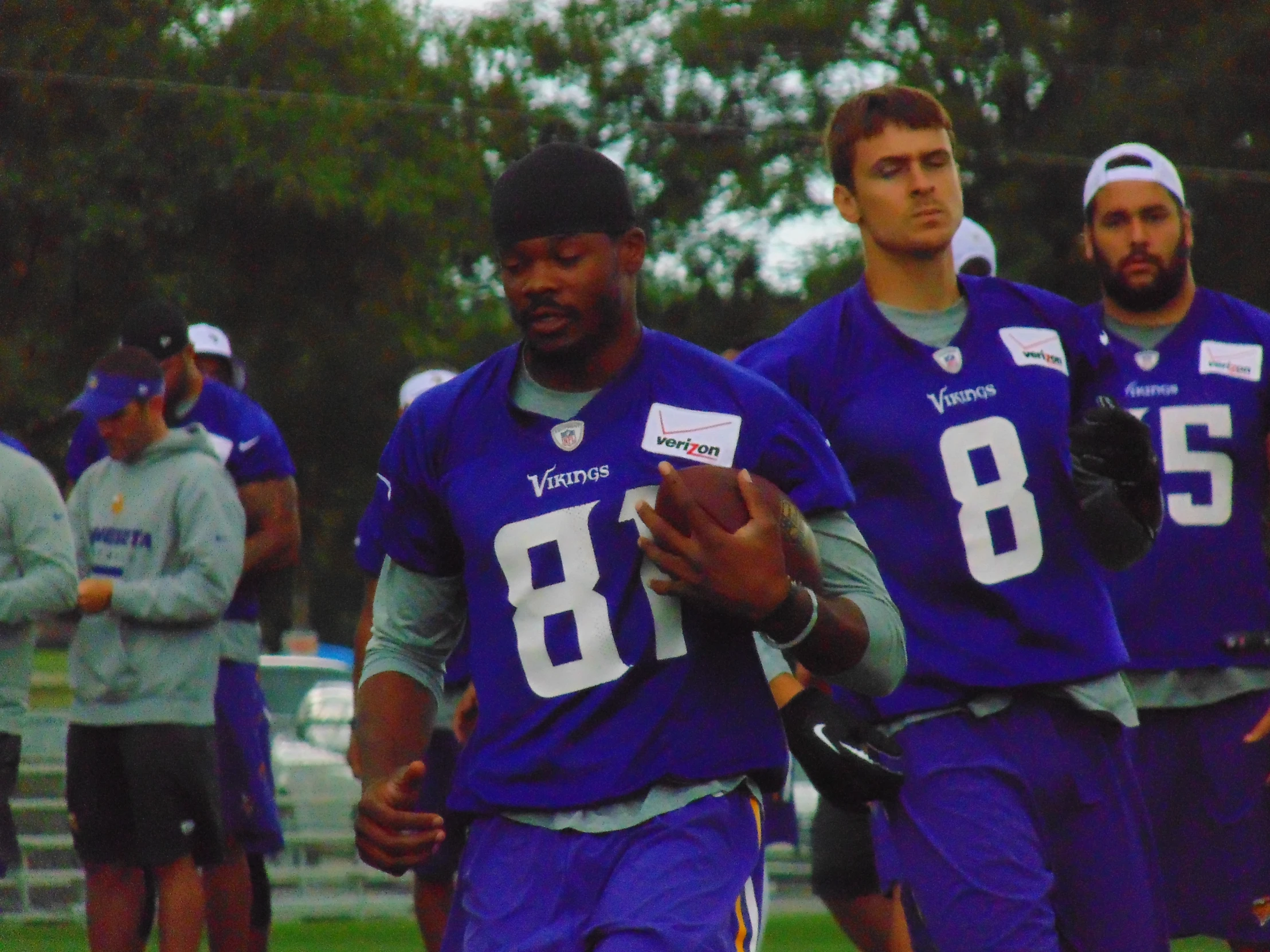 men in football uniforms holding hands at a practice