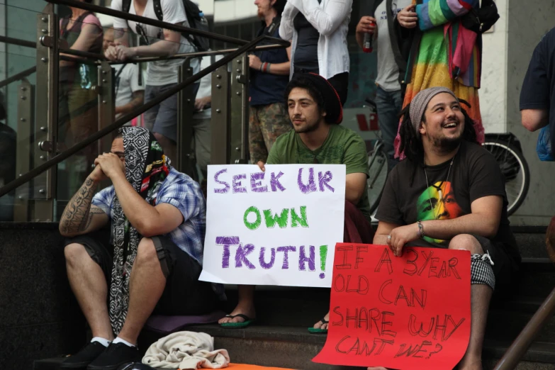 people sitting on steps with signs on them