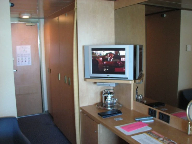 the television is on above a small desk in a el room