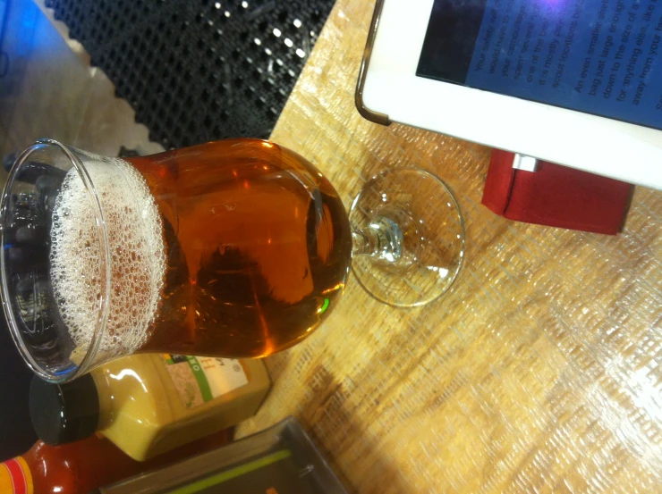 a close up of a glass of beer near a tablet