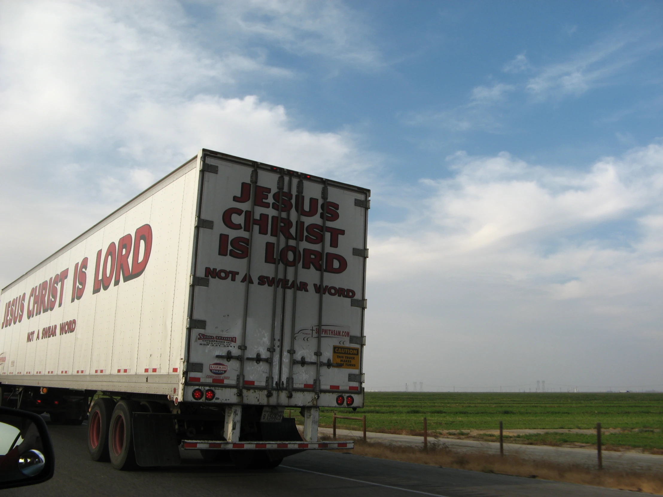 a truck driving down a road on the side of a road