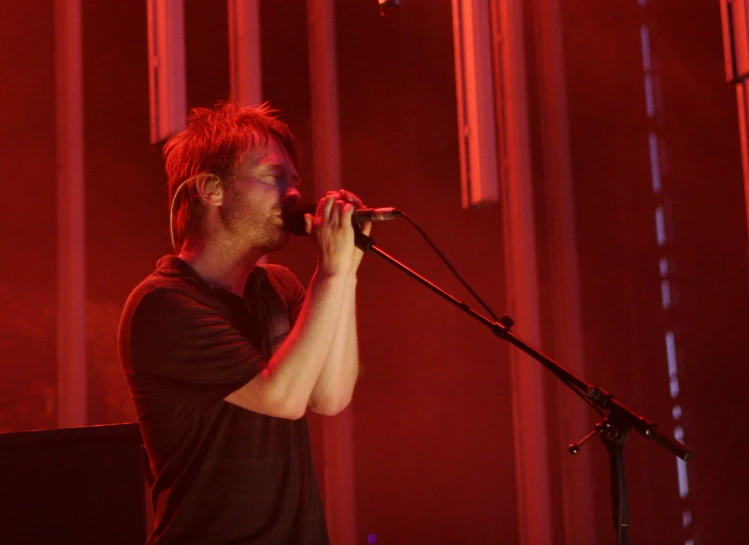 a young man singing into a microphone at a concert