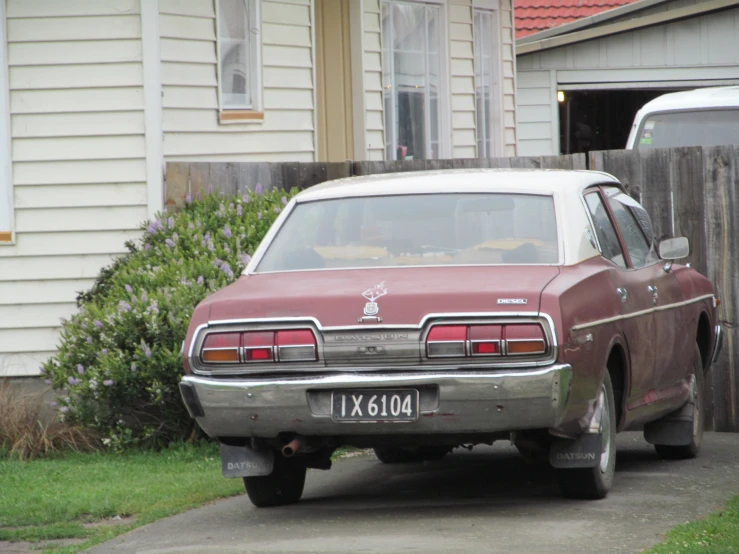 an old and worn red car is parked by the curb