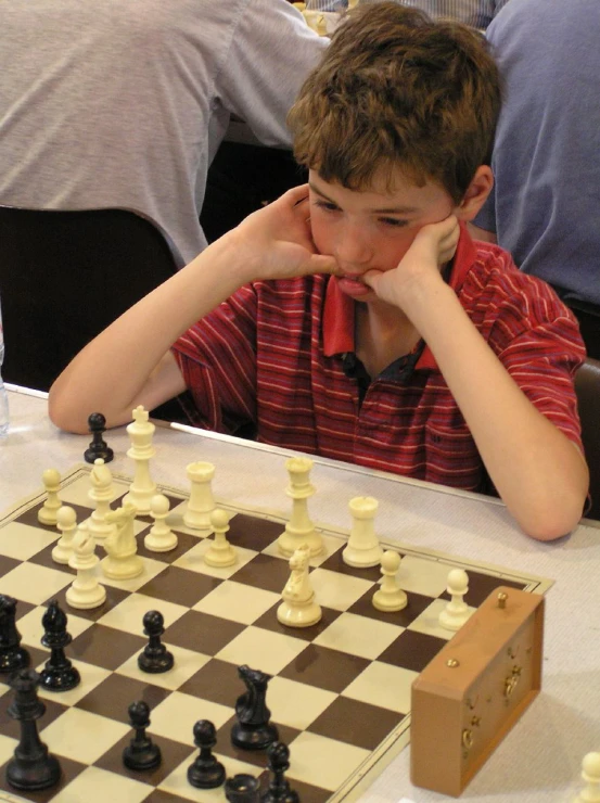 a boy who is sitting down next to a chess game