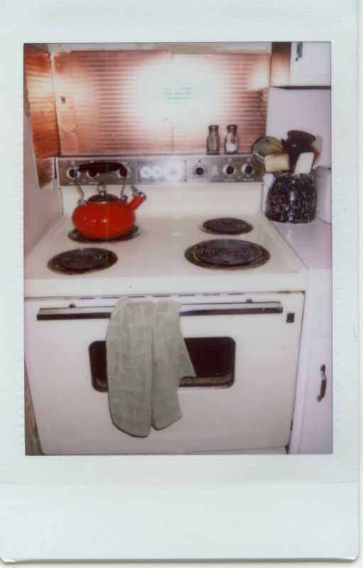 an old stove with tea kettle, pot, and kettle on top