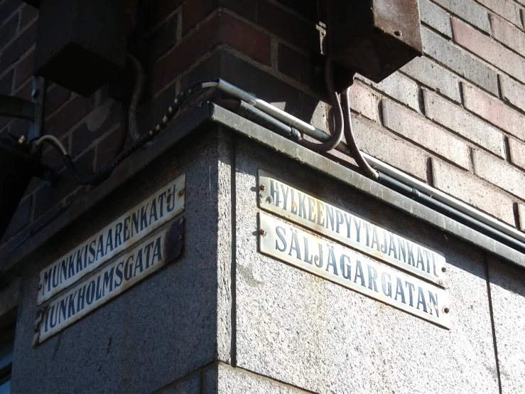 street name signs displayed at the corner of a building