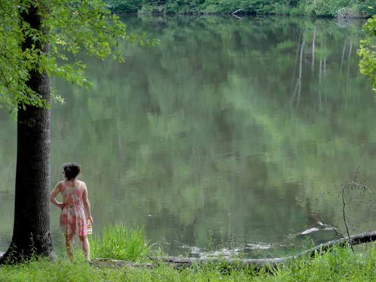 a woman standing by a river looking at the water