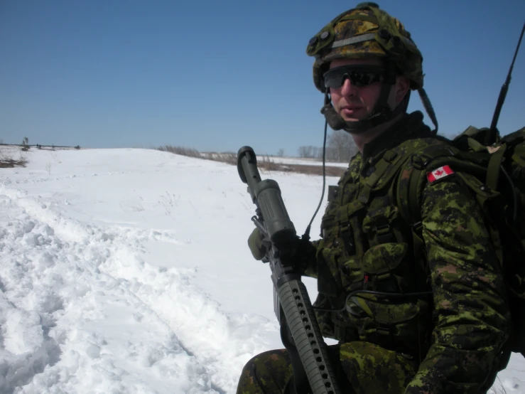 a man in fatigues holds up a rifle with another soldier near by