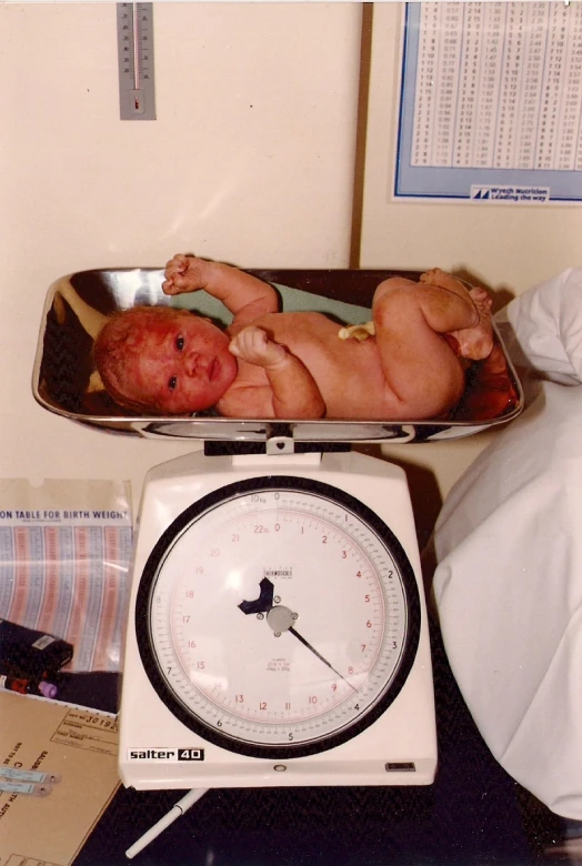 an infant is being weighed in a weighing scale