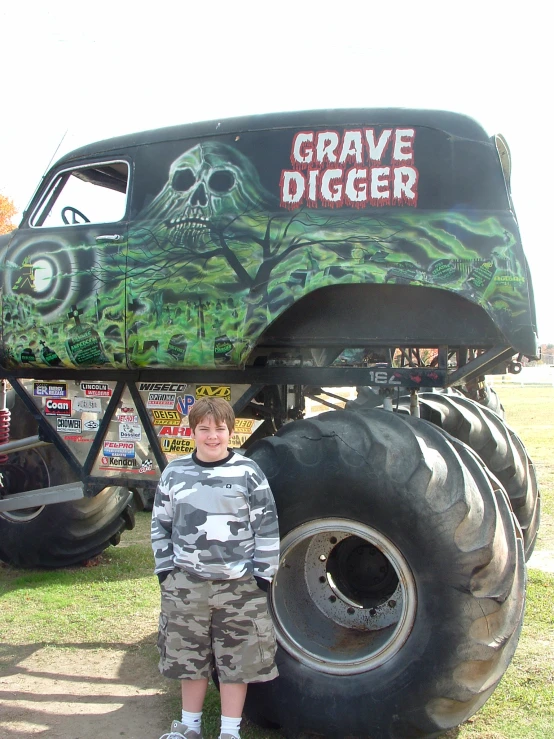 a  posing in front of a large monster truck