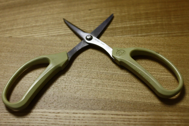 the green scissors are all around the wooden table