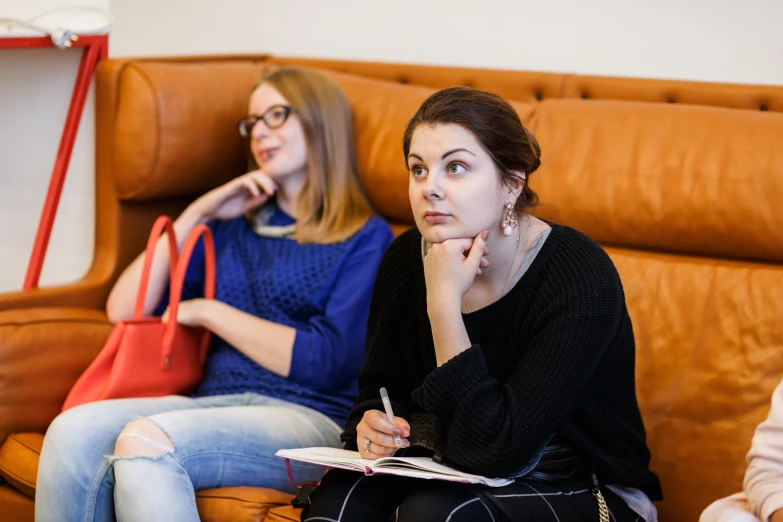 two beautiful young women sitting on a couch next to each other