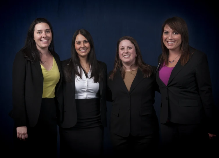 five women are posing in suits, they are all smiling for the camera