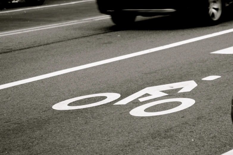 a bicycle path sign on the road that is black and white