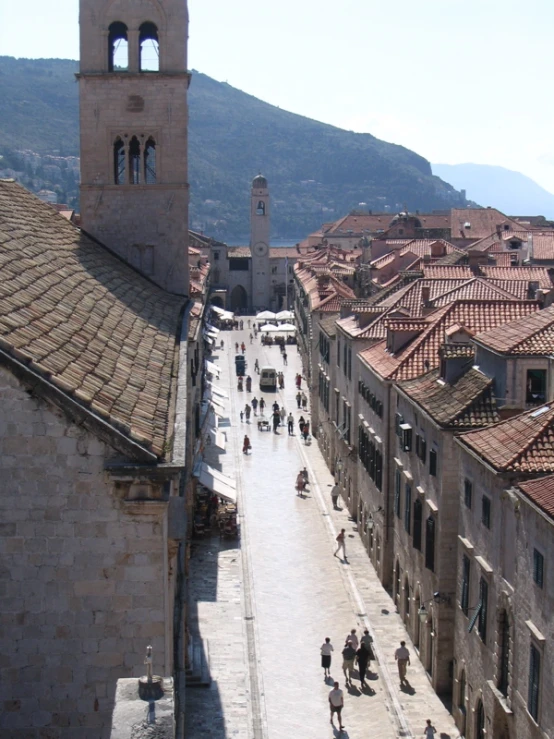 the people are walking along the street near the mountains