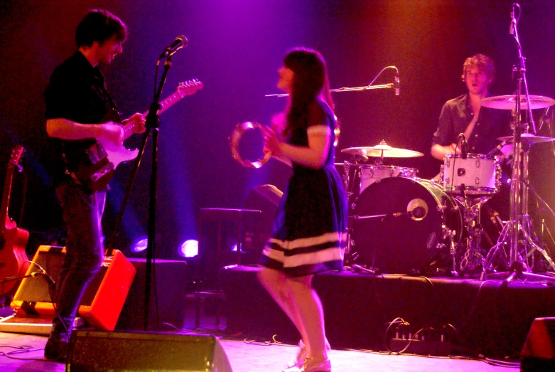 a woman on stage while an adult musician plays on the bass