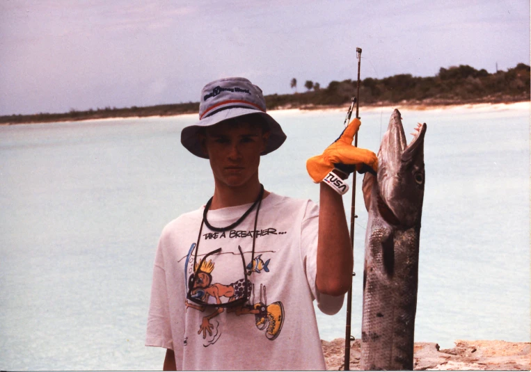 a young man holding a fishing pole next to a fish