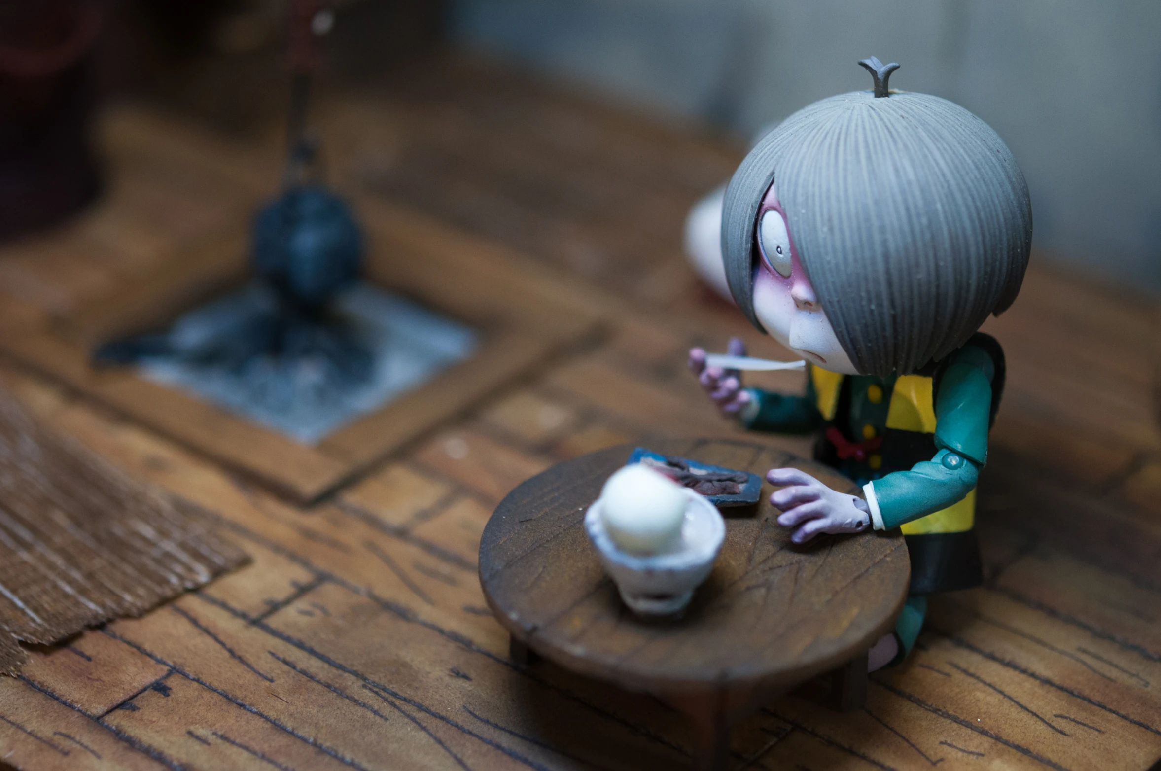 a doll sits at a table with a cup of coffee