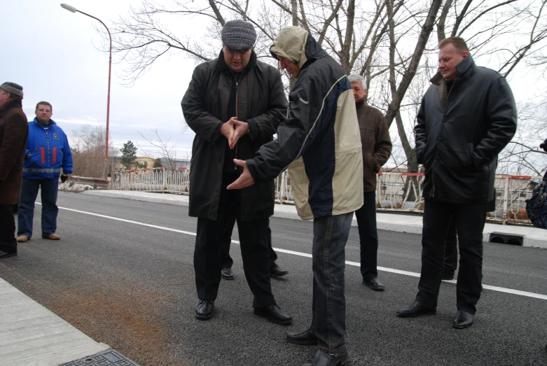 men in jackets are standing on a street corner