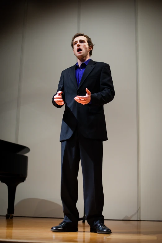 a man wearing black with blue shirt and tie