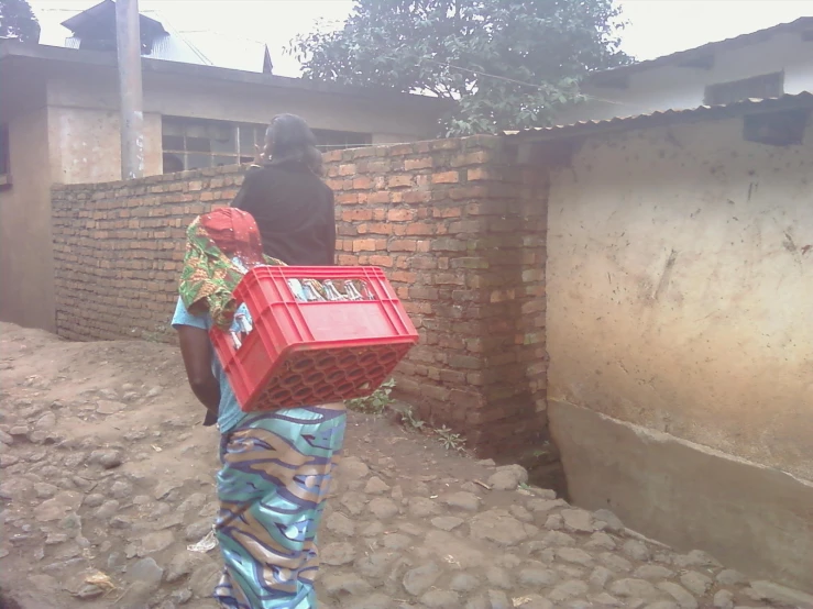 an african woman carrying some red baskets