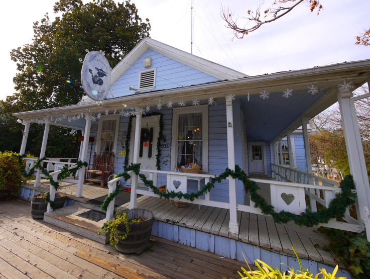 a small blue house decorated with christmas garland and lights