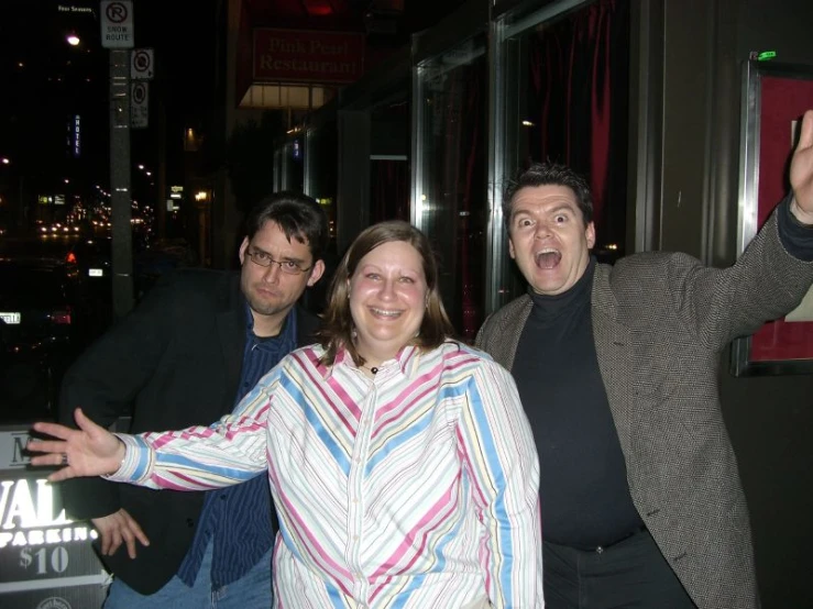 three people pose for a po in front of a neon sign