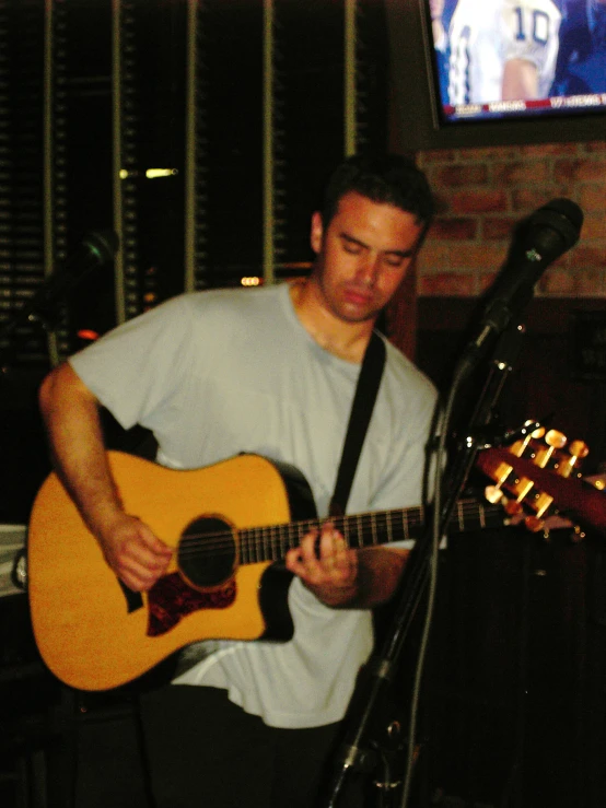 a man plays guitar in front of a tv