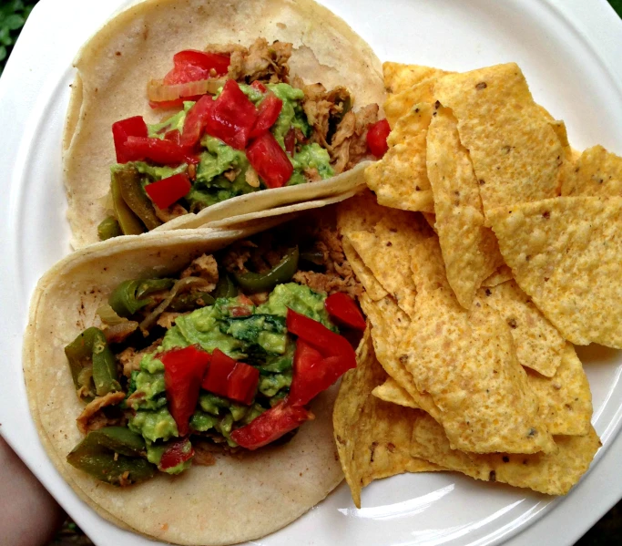 three tacos with a variety of vegetables, and tortillas chips