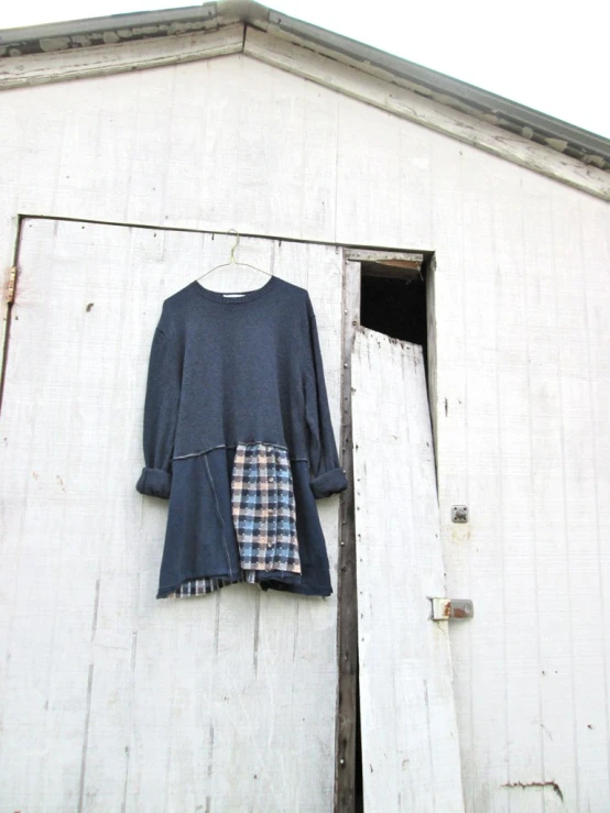 an old fashion plaid shirt hanging on the side of a white building