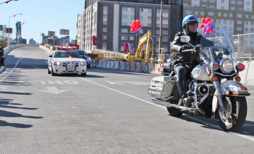 a police officer rides his motorcycle in traffic down the street